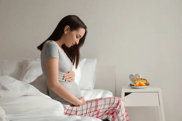 Beautiful pregnant woman sitting on bed in morning — Stock Photo, Image