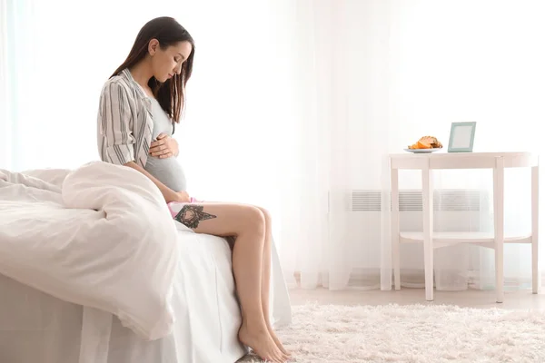 Beautiful pregnant woman sitting on bed in morning — Stock Photo, Image