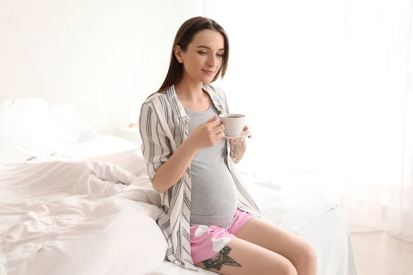 Beautiful pregnant woman drinking coffee on bed in morning — Stock Photo, Image