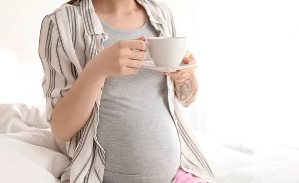 Красива вагітна жінка п'є каву на ліжку вранці — стокове фото