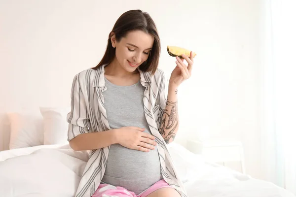 Hermosa mujer embarazada con rebanada de piña en la cama por la mañana — Foto de Stock