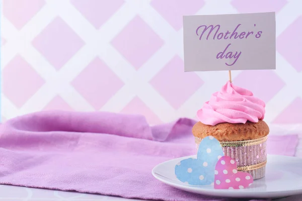 Tasty cupcake and card with words MOTHER'S DAY on table — Stock Photo, Image