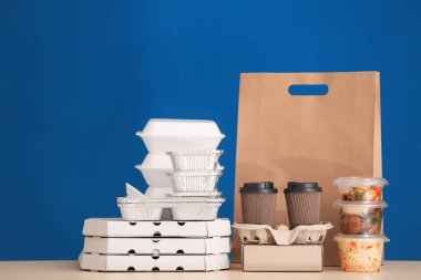 Farklı paketleri masasına renk arka plan karşı lezzetli yemek ile. Teslimat hizmeti