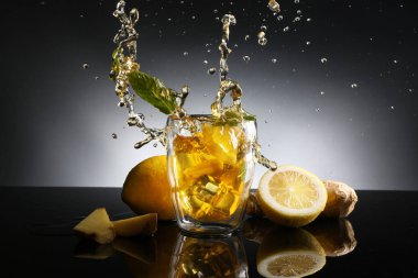 Limonlu çay koyu arka plan üzerinde sıçrama ile bardak