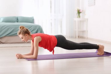 Evde yoga yapan genç bir kadın.