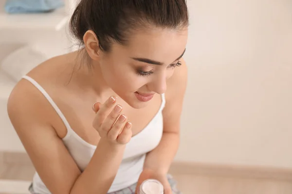 Jovem mulher aplicando creme facial de manhã — Fotografia de Stock
