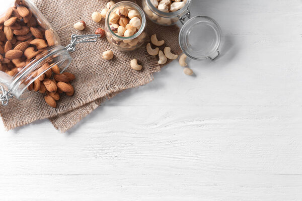 Composition with different types of nuts on white wooden background