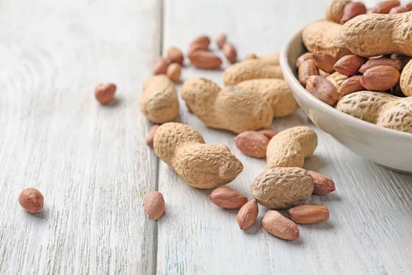 Bowl with peanuts on wooden background — Stock Photo, Image