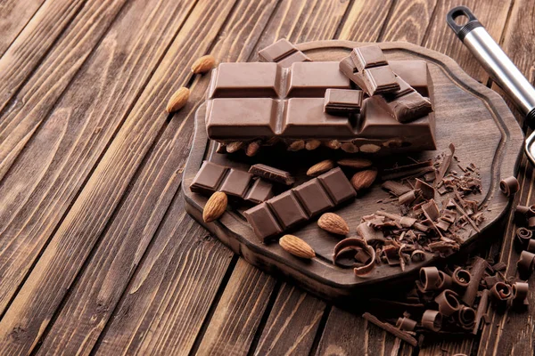 Schokoladentafel mit Mandeln auf Holzbrett — Stockfoto