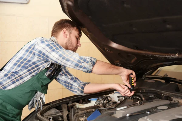 Joven mecánico de automóviles de reparación de coches en el centro de servicio — Foto de Stock