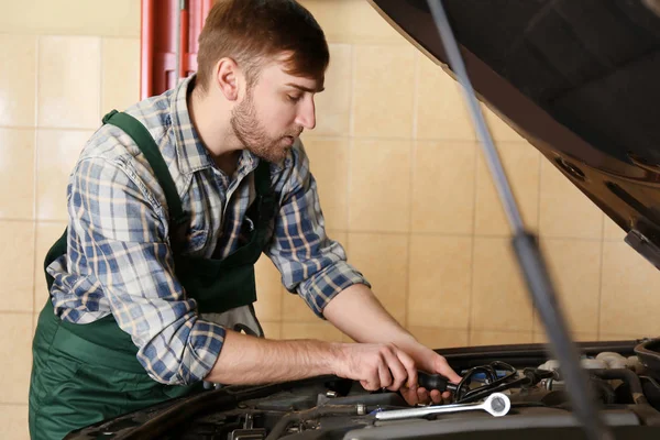 Joven mecánico de automóviles de reparación de coches en el centro de servicio — Foto de Stock