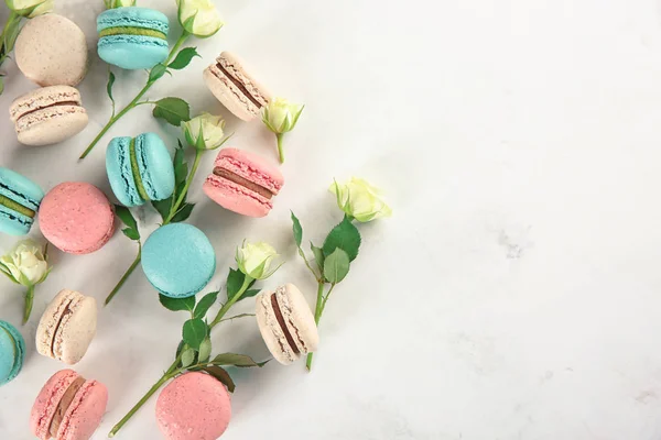 Flat lay composition with tasty macarons and roses on light background — Stock Photo, Image