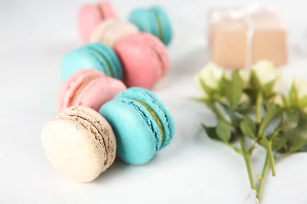 Tasty macarons and roses on light background — Stock Photo, Image