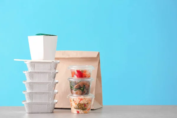 Verschillende pakketten met heerlijk eten op tafel tegen een achtergrond met kleur. Leveringsservice — Stockfoto