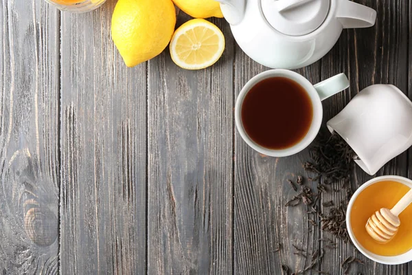 Чашка вкусного чая с медом и лимоном на деревянном столе — стоковое фото
