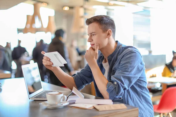 Молодий чоловік читає листа за столом у кафе. Доставка пошти — стокове фото