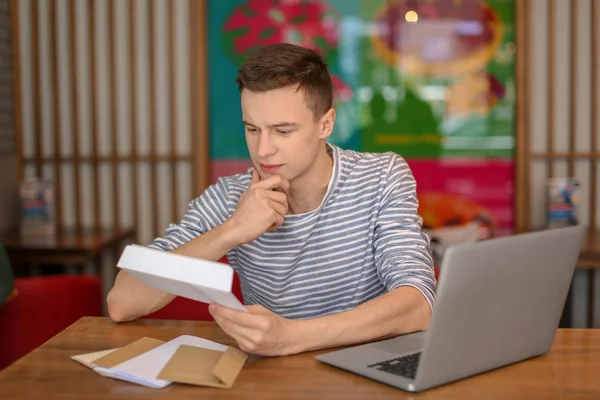 Молодий чоловік читає листа за столом у кафе. Доставка пошти — стокове фото
