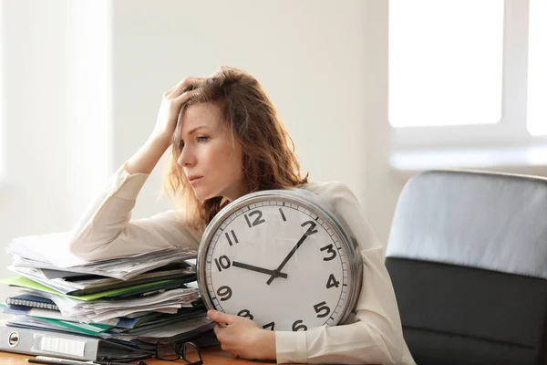 Reife, müde Frau mit Uhr am Tisch im Büro. Zeitmanagement-Konzept — Stockfoto