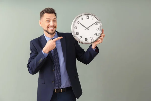 Empresário com relógio sobre fundo de cor. Conceito de gestão do tempo — Fotografia de Stock