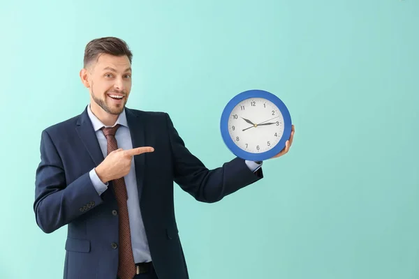 Homme d'affaires avec horloge sur fond de couleur. Concept de gestion du temps — Photo