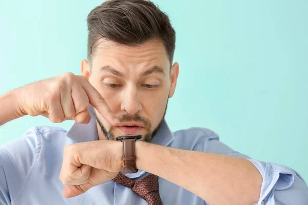 Hombre mirando reloj de pulsera sobre fondo de color. Concepto de gestión del tiempo — Foto de Stock