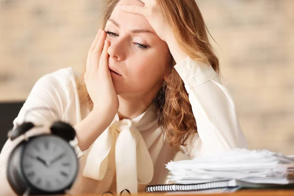 Reife, müde Frau mit Wecker am Tisch im Büro. Zeitmanagement-Konzept — Stockfoto
