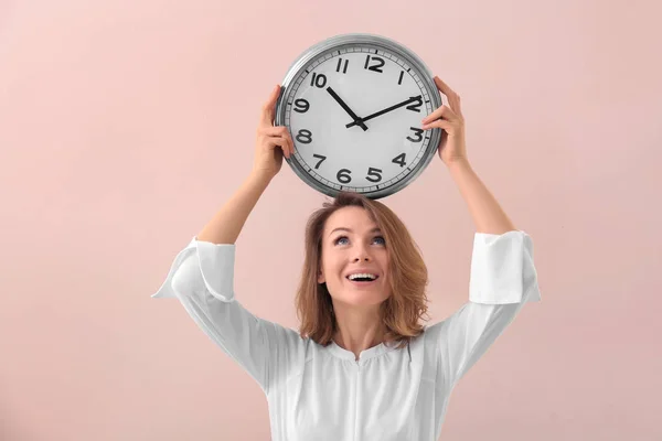 Reife Frau mit Uhr auf farbigem Hintergrund. Zeitmanagement-Konzept — Stockfoto