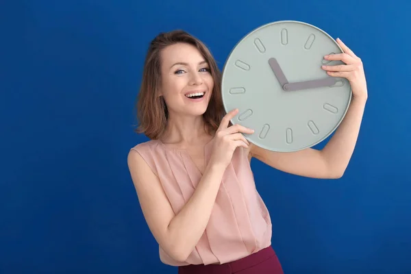 Mujer madura con reloj sobre fondo de color. Concepto de gestión del tiempo —  Fotos de Stock