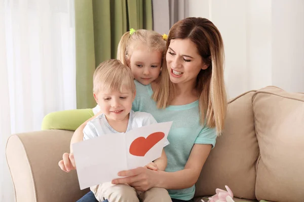 Moeder ontvangende wenskaart uit haar schattige kleine kinderen thuis — Stockfoto