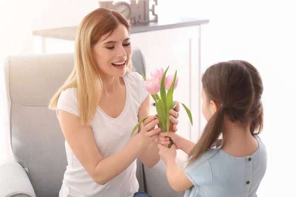 Mother receiving flowers from her cute little daughter at home — Stock Photo, Image