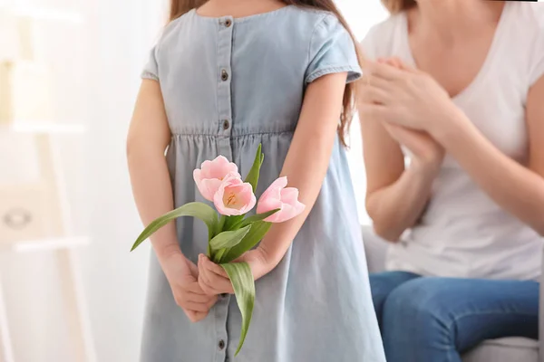 Söt liten flicka gömmer sig blommor för mor bakom hennes rygg — Stockfoto
