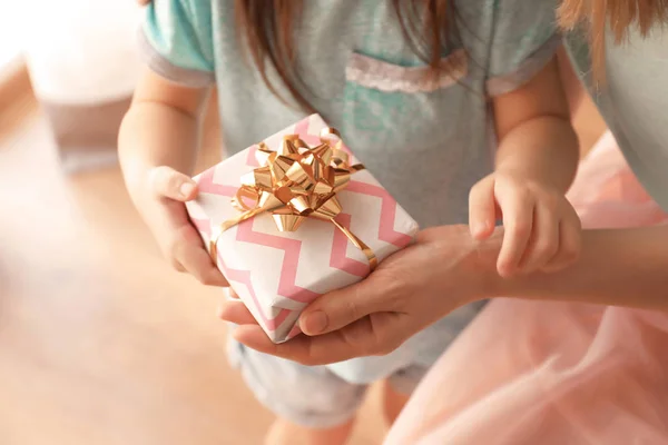 Mother receiving gift from her cute little daughter at home, closeup