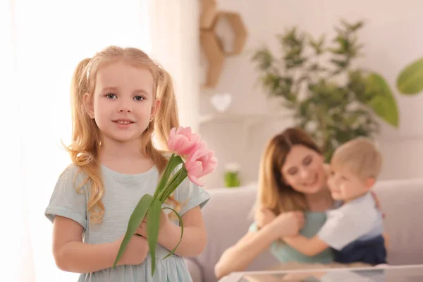 Cute little girl with flowers for her mother at home — Stock Photo, Image