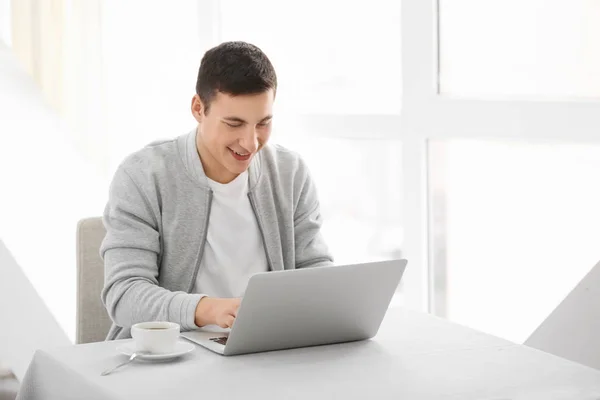 Young man working with laptop at table in cafe — Stock Photo, Image