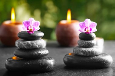 Güzel çiçekler ve mumlar masada açık havada Spa taşlarla