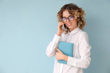 Cep telefonu tarafından renk arka plan üzerinde konuşurken resmi giysili güzel genç kadın