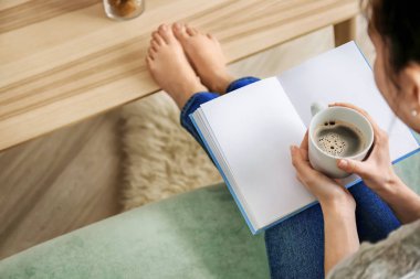 Genç kadın evde kitap okurken kahve içme