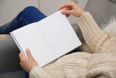 Evde kitap okuyan genç bir kadın.