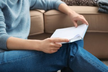 Evde kitap okuyan genç bir kadın.