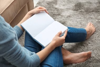 Evde kitap okuyan genç bir kadın.
