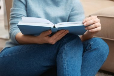 Evde kitap okuyan genç bir kadın.