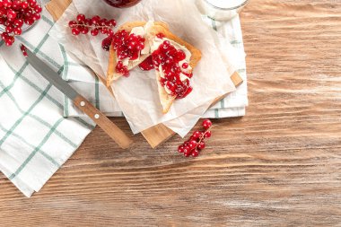 Ahşap tahta üzerinde kırmızı kuş üzümü ile lezzetli tost