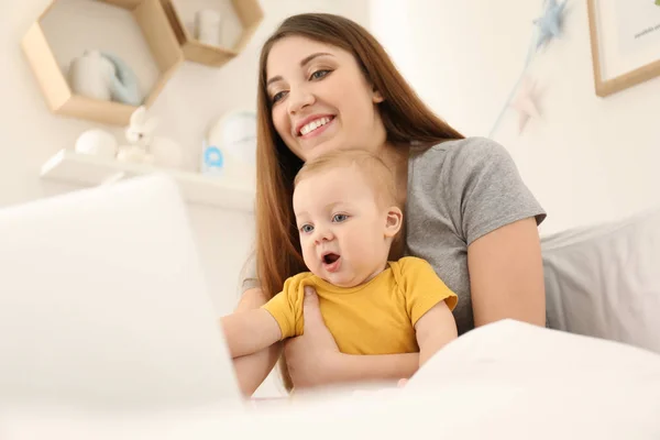 Joven madre con bebé trabajando en la cama en casa — Foto de Stock