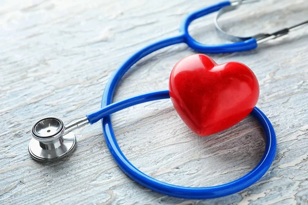 Stetoscopio con cuore rosso su sfondo di legno. Concetto sanitario — Foto Stock