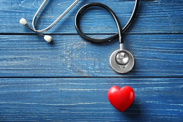 Estetoscópio com coração vermelho sobre fundo de madeira. Conceito de saúde — Fotografia de Stock