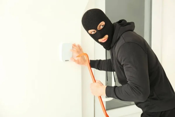 Ladrão masculino com pé de cabra quebrando sistema de segurança dentro de casa — Fotografia de Stock