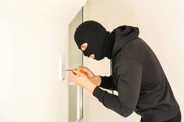 Ladrón masculino rompiendo sistema de seguridad con destornillador en interiores — Foto de Stock