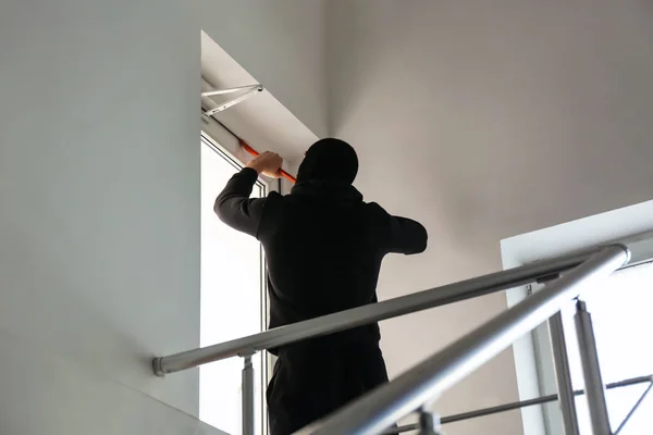 Male thief breaking door with crowbar indoors — Stock Photo, Image