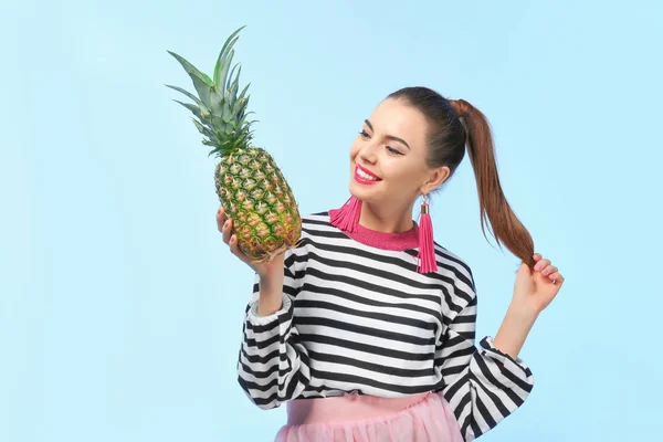 Aantrekkelijke jonge vrouw met ananas op kleur achtergrond — Stockfoto