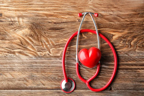 Stetoscopio e cuore rosso su sfondo di legno. Concetto sanitario — Foto Stock